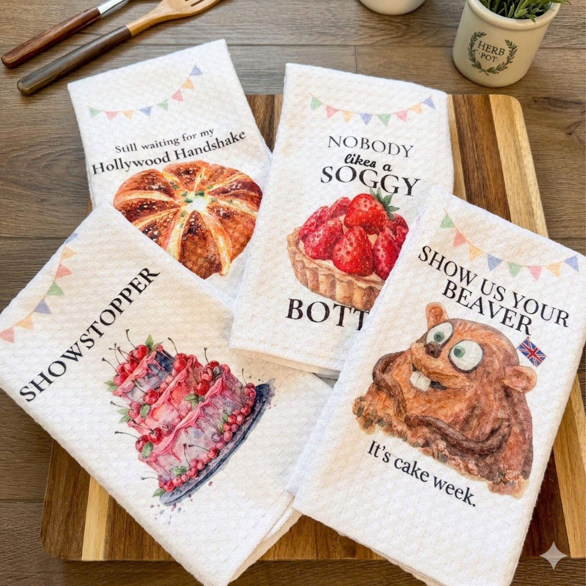 Set of four decorative towels with humorous designs on a wooden cutting board.