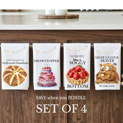 Four kitchen towels with humorous designs on a wooden cabinet.