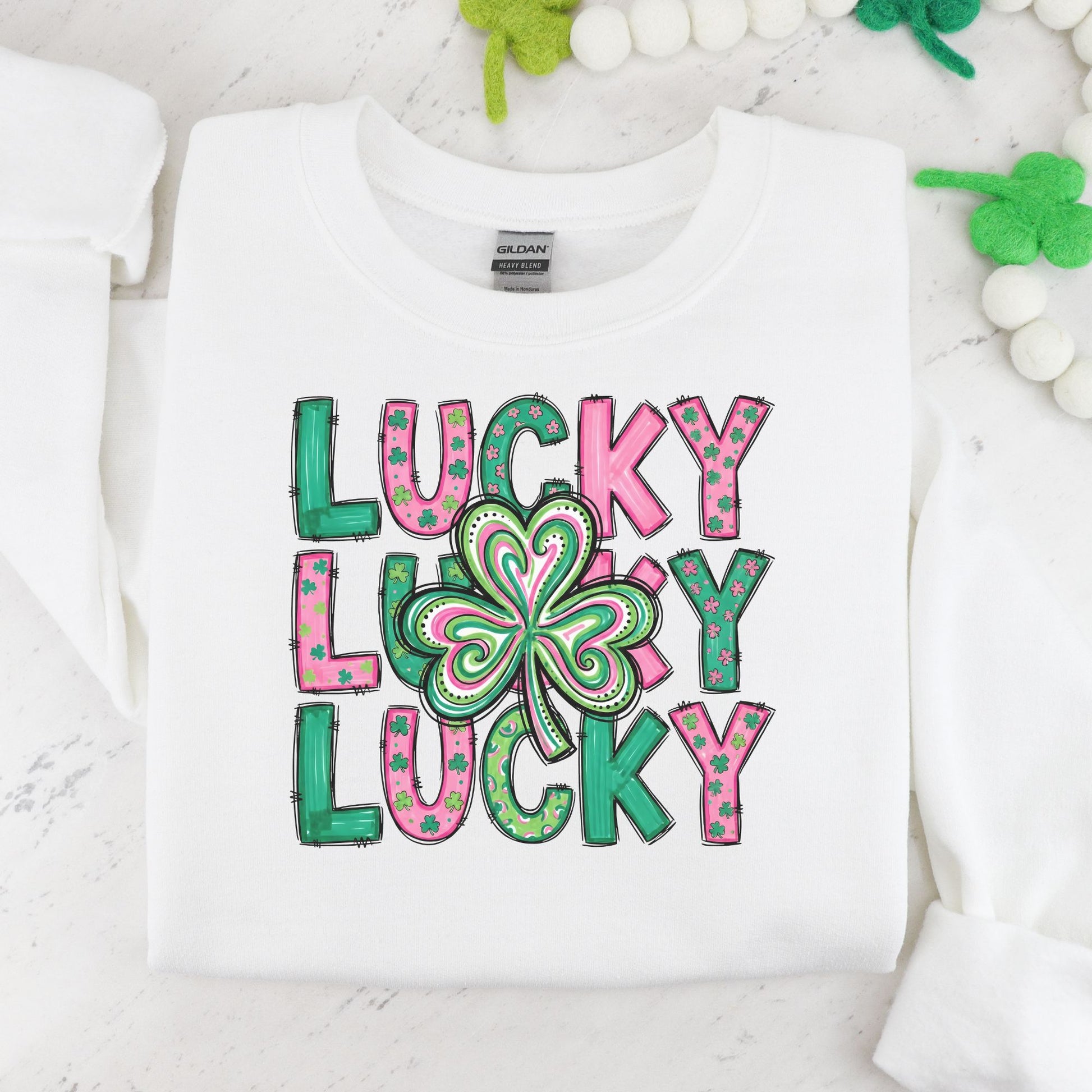 White St Patrick's Day crewneck sweatshirt with 'Lucky Lucky Lucky' text and four-leaf clover design on a marble surface.
