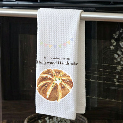 Kitchen towel with bread design and text hanging on an oven handle.