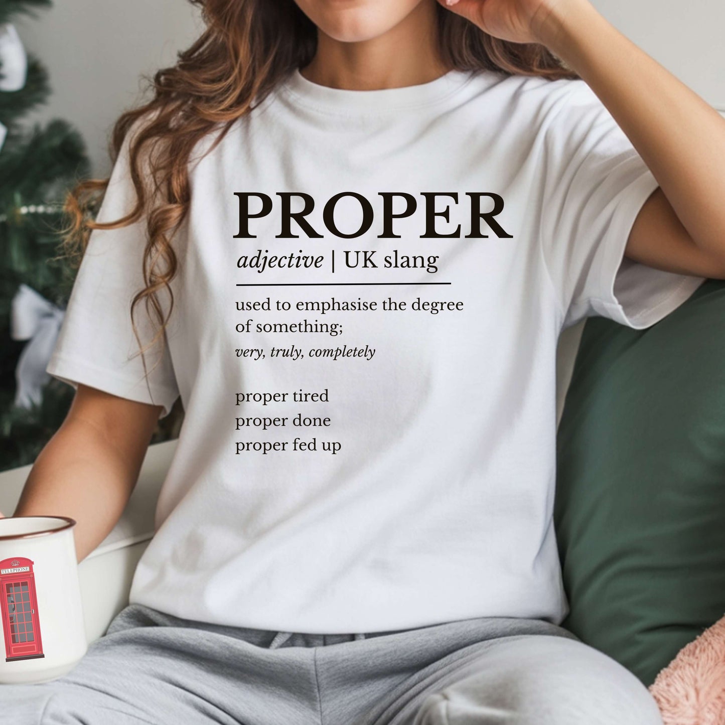 Person wearing a white t-shirt with the word 'PROPER' and its definition printed on it, sitting on a couch.