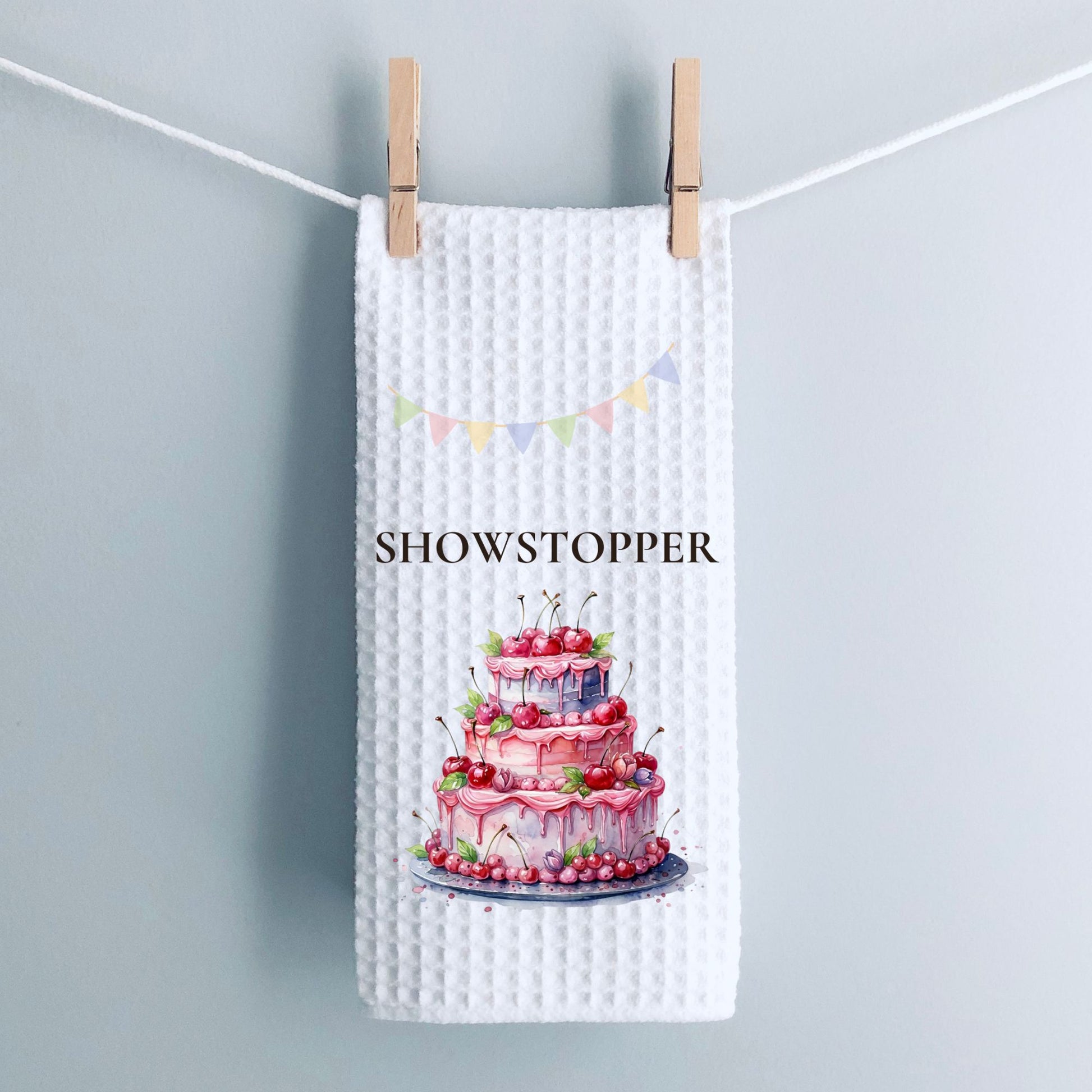 Waffle text towel with a cake design and 'SHOWSTOPPER' text, hanging on a line.