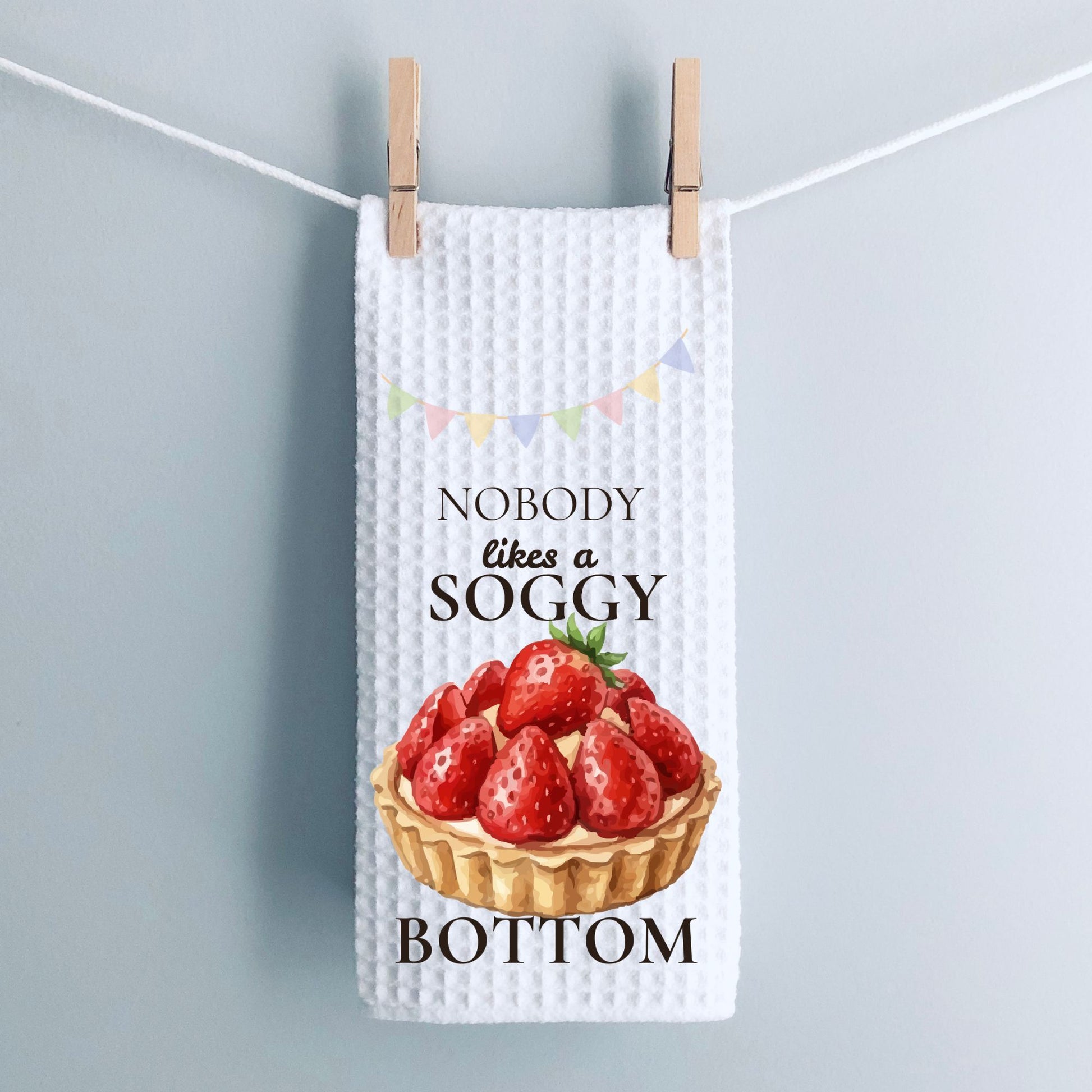 Waffle-textured tea towel with strawberry tart design and text on a light gray background