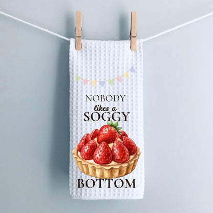 Waffle-textured tea towel with strawberry tart design and text on a light gray background