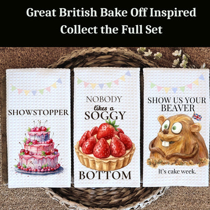 Three kitchen towels with humorous sayings inspired by 'Great British Bake Off' on a woven basket.