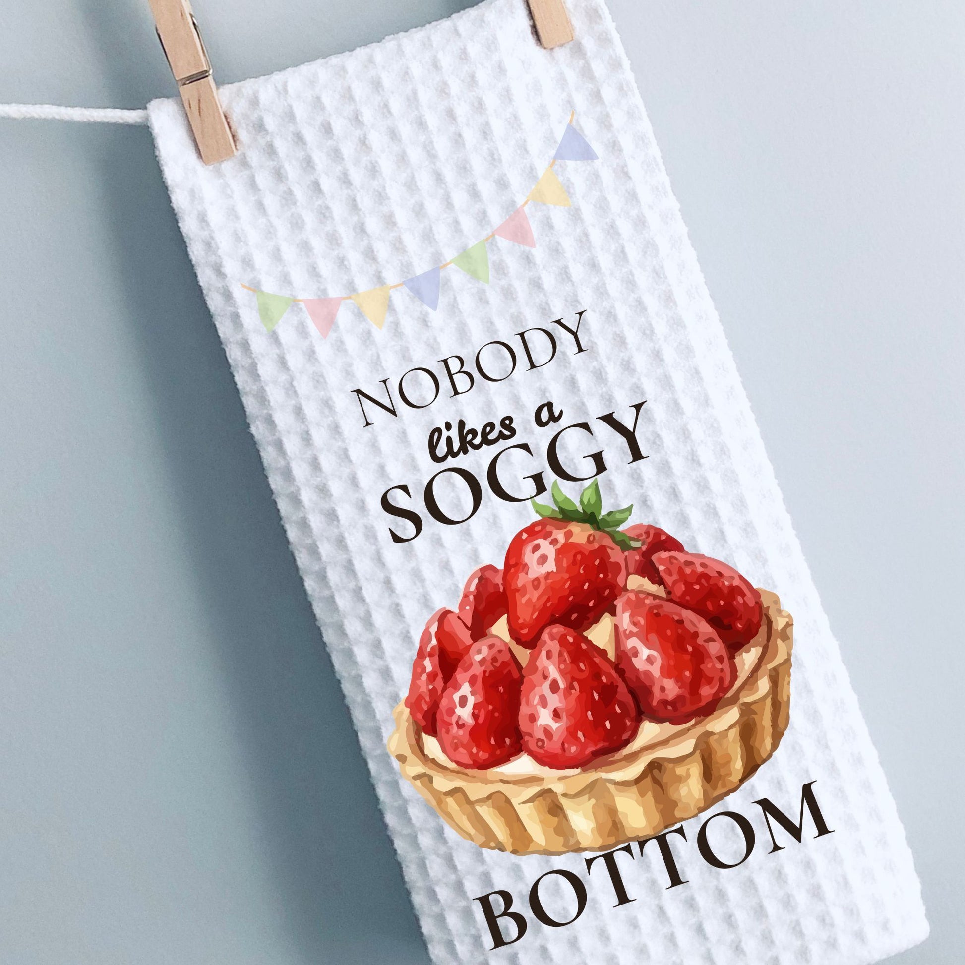 Kitchen towel with strawberry tart design and humorous text on a gray background