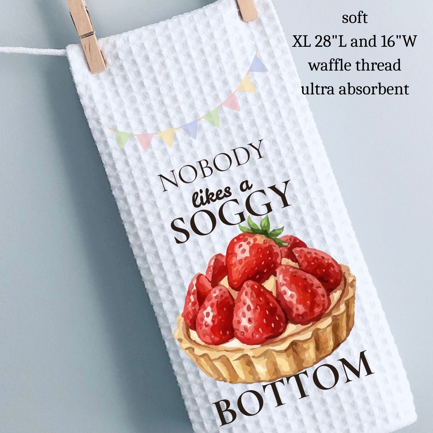 Waffle-textured towel with strawberry tart design and humorous text, hanging on a line.