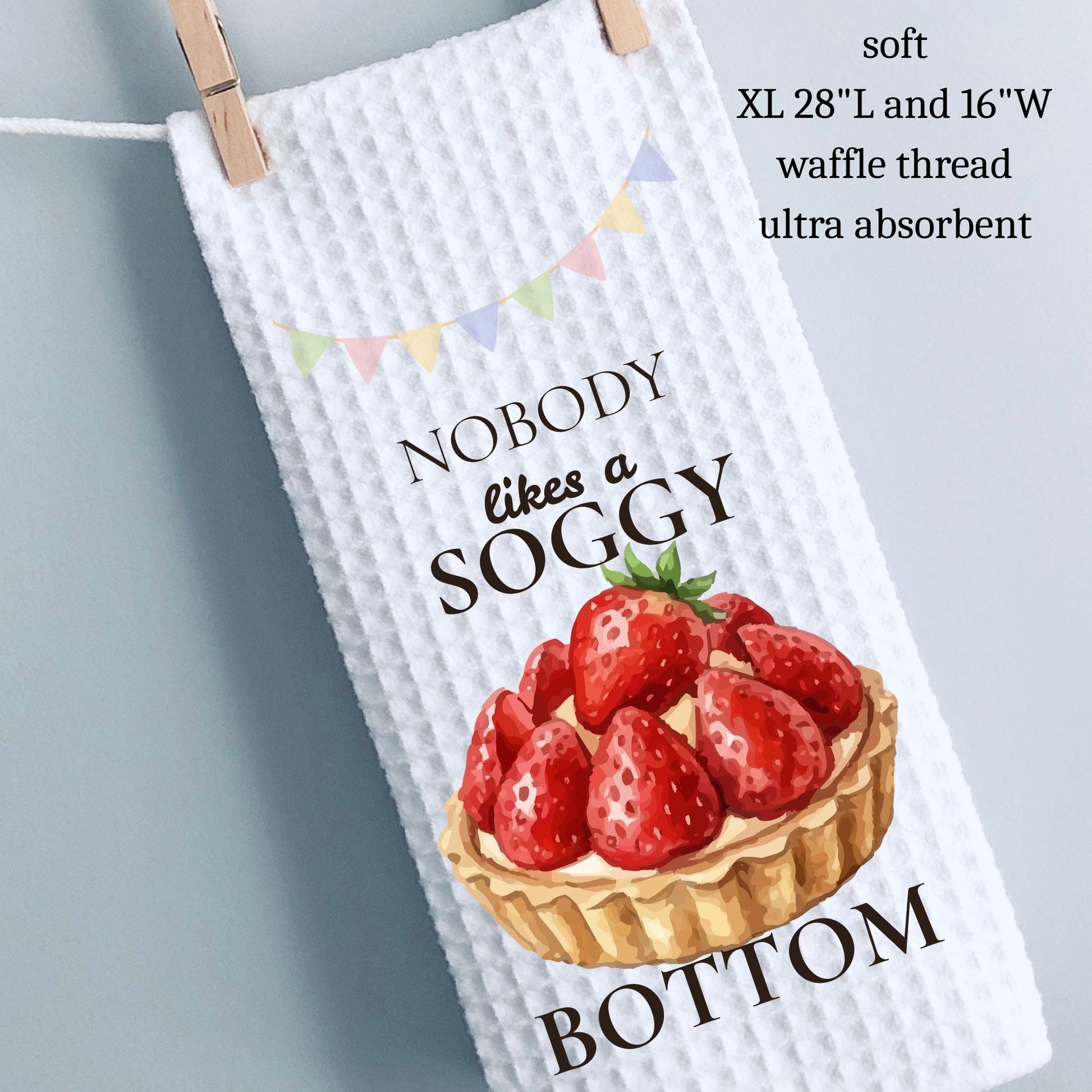 Waffle-textured towel with strawberry tart design and humorous text, hanging on a line.