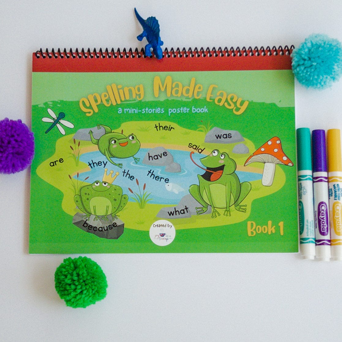 workbook cover depicting frogs with markers and children's toy surrounding it